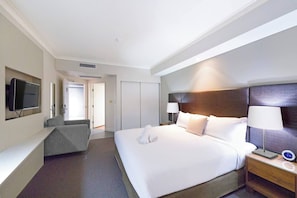 This spacious king studio offers built-in robes, TV, and window views over treetops and the sea.
