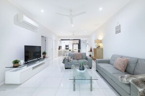A sleek, air-conditioned living area is furnished with comfortable couches, a glass coffee table and a flat-screen TV.