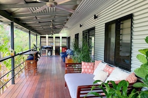 A spacious and private rear deck offers al fresco bar-top dining facing the lush garden alongside a comfortable day bed