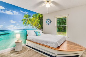 Anchors aweigh in this charming bedroom featuring full/double-sized boat beds with a twin trundle, and a coastal mural, offering a whimsical retreat for the perfect sleepover setup