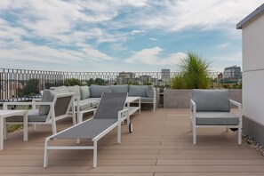 Rooftop terrace with lounge chairs and stunning views of the city skyline.

