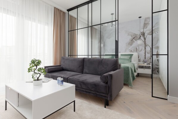 Bright living room with a comfortable grey sofa, white coffee table, and elegant glass partition.

