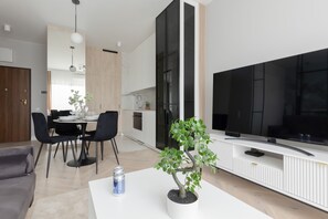 Open-plan living and dining area featuring a sleek design and a wall-mounted TV.

