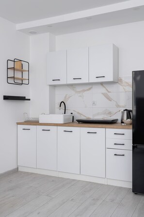 Modern kitchen with white cabinets, marble countertops, and a compact yet functional design.

