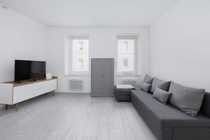 Living room with a grey sofa, flat-screen TV, and light wood furniture creating a cozy ambiance.

