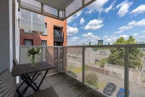 Balcony with a small table and chairs, overlooking a well-maintained residential area.

