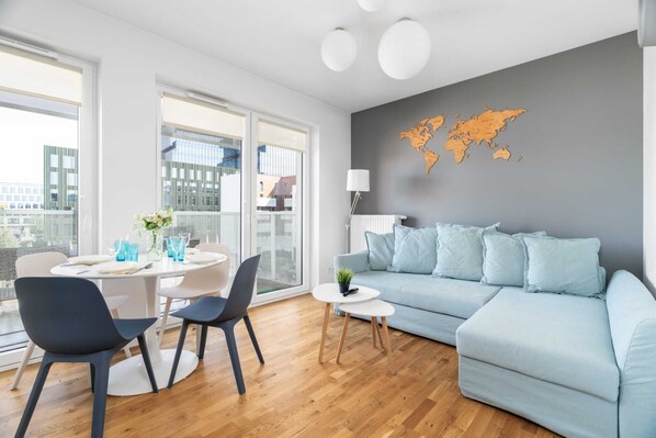 Bright living room with a modern blue sofa, wooden flooring, and a world map wall decor.

