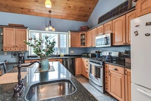 Spacious kitchen has lots of storage and and an island with 3 barstools.