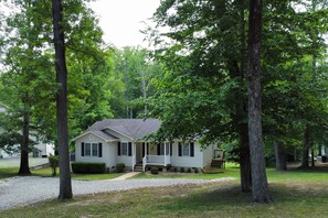 Cottage through trees from open area at top of property.