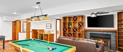 [Entertainment Area, Basement] 65" TV, pool table, foosball table, fireplace, half bathroom, and access to patio
