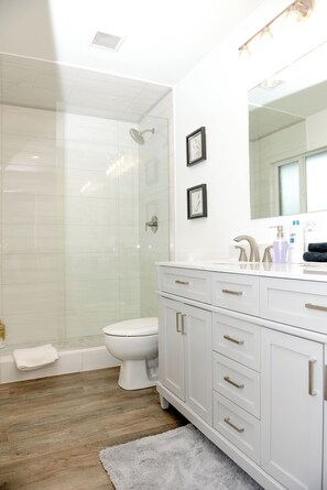 Upstairs primary bathroom with double vanity and beautifully tiled shower