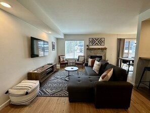 Living room with large flatscreen TV, newly remodeled flooring.