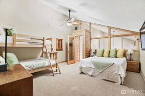 Spacious bedroom featuring a cozy queen bed and a unique queen bunk bed, perfect for accommodating your group comfortably.