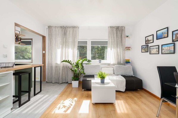Bright living room with modern furniture, wooden flooring, and large windows for natural light.

