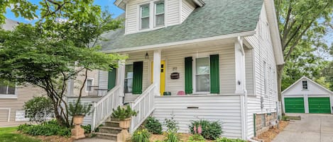 The entrance of the house adorned with a vibrant yellow door complemented by refreshing green window panels.