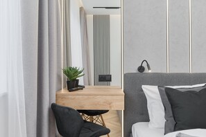 A bedside table with a mirror and a plant, adding a natural touch to the bedroom.

