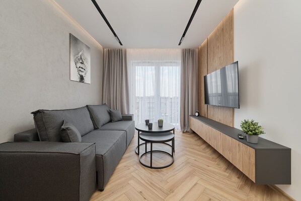 A modern living room with a comfortable gray sofa, a wooden entertainment unit, and a sleek TV setup.

