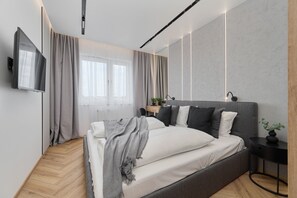A cozy bedroom with soft lighting, gray bedding, and a stylish wooden accent wall.

