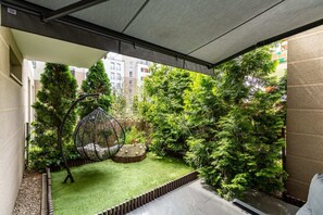 A private garden with green hedges and a shaded seating area for outdoor relaxation.

