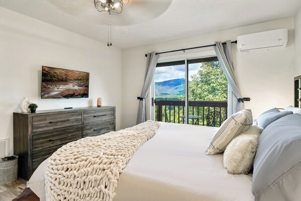 2nd bedroom with bed, dresser, smart tv, and mountain view from this angle.