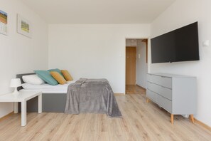 A cozy room with a bed, a sofa, and a TV mounted on the wall for comfort and relaxation.

