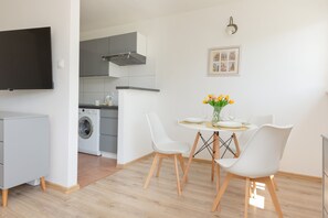 A dining nook with a small table, two chairs, and a modern setup near a kitchenette.

