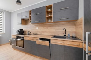 A modern kitchen with wooden finishes, dark cabinets, and stainless steel appliances for a sleek look.

