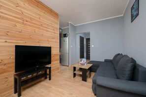 Another angle of the living room showcasing the TV area and wooden panel walls.

