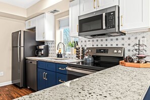 Savor the blend of classic charm and modern flair in this kitchen, where bold blue cabinets and elegant geometric tiles inspire culinary creativity