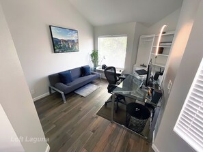 Office area with 34" monitor, Herman M chair, PS4, and retractable sofa bed.