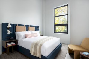 King Bed with plush linens, armchair, large closet, noise cancelling machine, hangers, bedside lamp, noise cancelling windows, and blackout shades. 