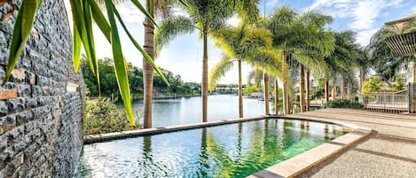 Spend summer days lazing by the waterfront, sun-soaked  outdoor pool that is framed by lush palm trees
