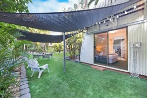 The landscaped garden provides alfresco dining and armchairs under the shade.