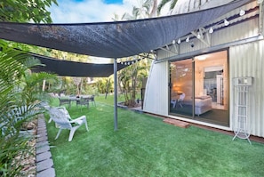 The landscaped garden provides alfresco dining and armchairs under the shade.