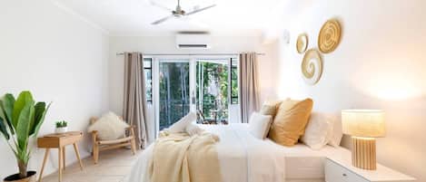 The sun-drenched master bedroom comes furnished with a plush king bed, black-out blinds, air conditioning, clothing storage, and direct balcony access.

