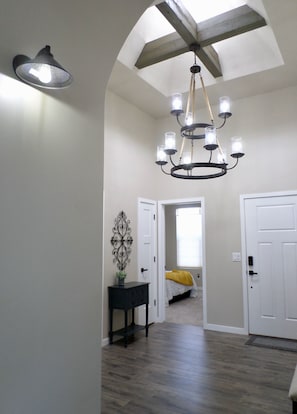 Entry way opens with dramatic high ceiling, chandelier, exposed beams skylight.