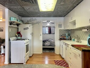 Range, fridge, dishwasher, double drainboard sink, pots, pans, and dishes. 