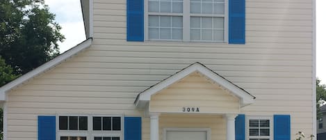 Front of the house adorned with beautiful greenery and a fully enclosed fence.