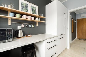 A modern kitchen with open shelving, white cabinets, and a clean, functional design.

