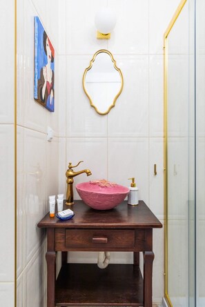 A compact bathroom with classic decor, including a vintage mirror and a pink sink.

