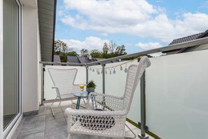 A charming balcony with a small table and chairs, offering a view of the rooftops.

