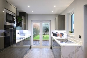 Modern kitchen with complete amenities, featuring a convenient back door for easy access to the back lawn.