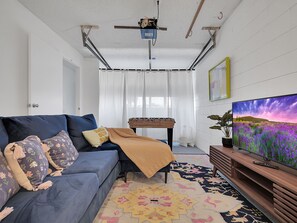 Living room on first floor with game table and 34' smart TV.