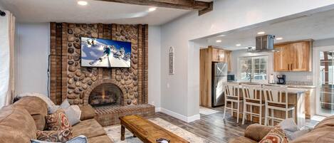 Cozy ambiance with stoned fireplace, comfy sofa, and natural light.