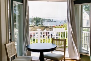 Room 13 features a bistro table and chairs by French doors that open to a private balcony with stunning views of Boothbay Harbor—perfect for morning coffee or sunset wine overlooking the water.