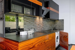 Functional kitchenette with sleek and modern furnishings. A washing machine is concealed in the cupboard.