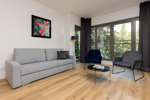Living room with a sofa bed, TV and exit to balcony.