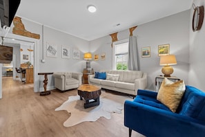 Living room with custom made live edge tables, leather couch & cozy chairs