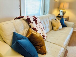 Plush pillows & blankets on the leather couch, 60” smart TV & board games