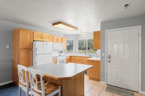 Kitchen - fridge/freezer, electric stove, fully stocked with dishes and coffee maker.